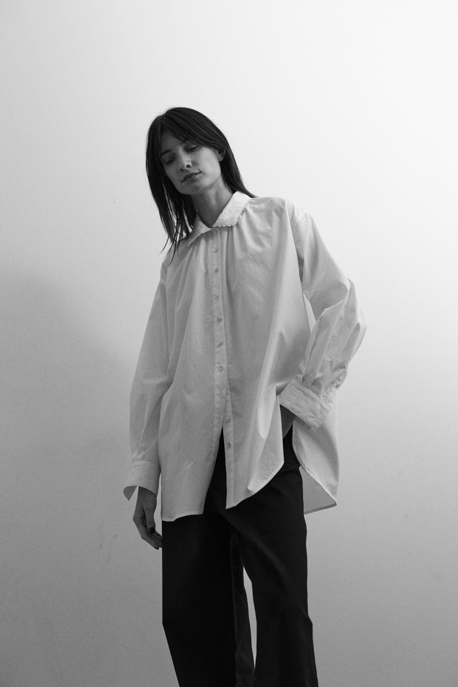 Person wearing an oversized white shirt against a plain background
