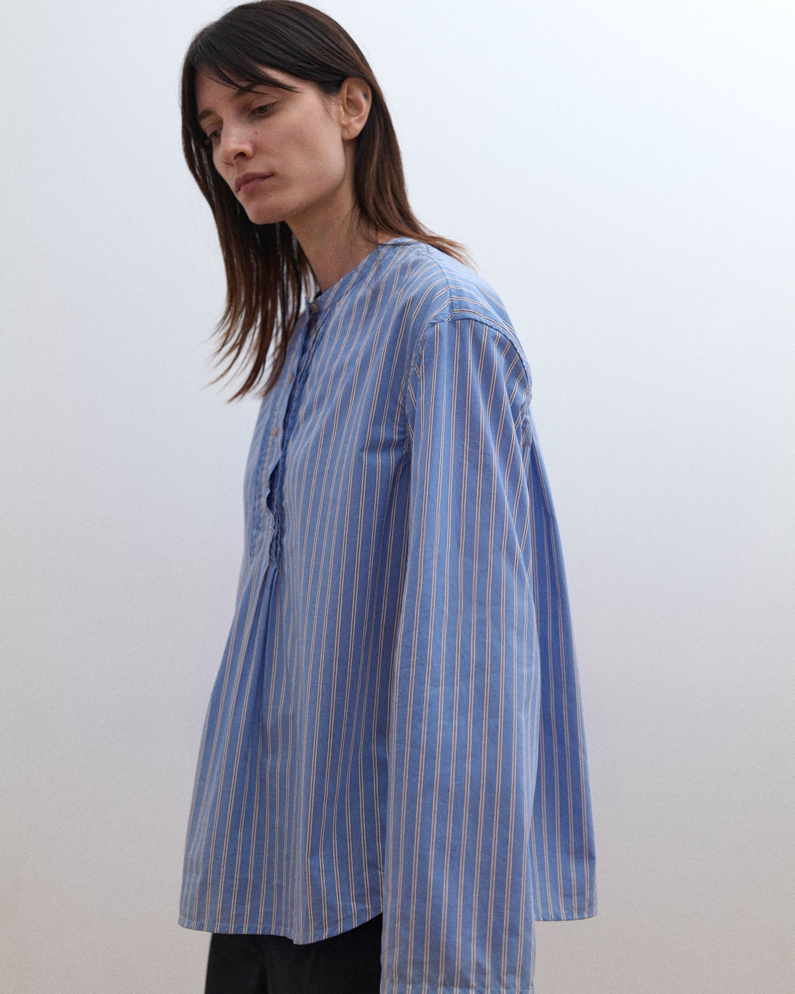 Woman wearing a blue and white striped shirt against a plain background