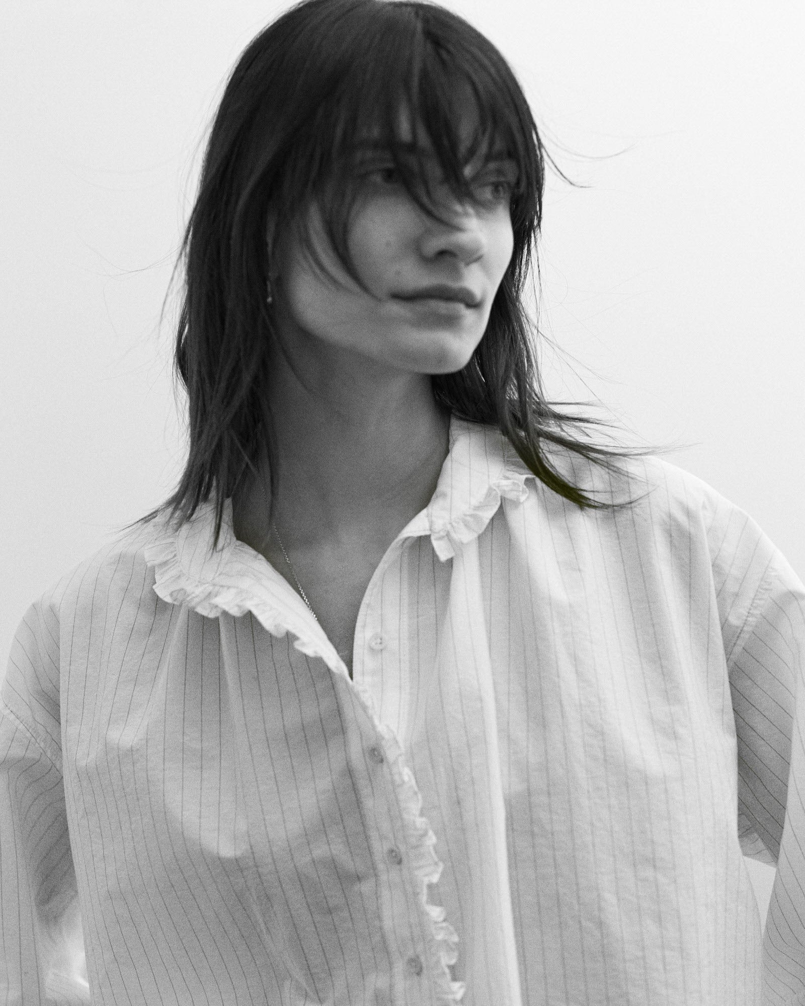 Black and white photo of a woman wearing a light-colored shirt with ruffled details.