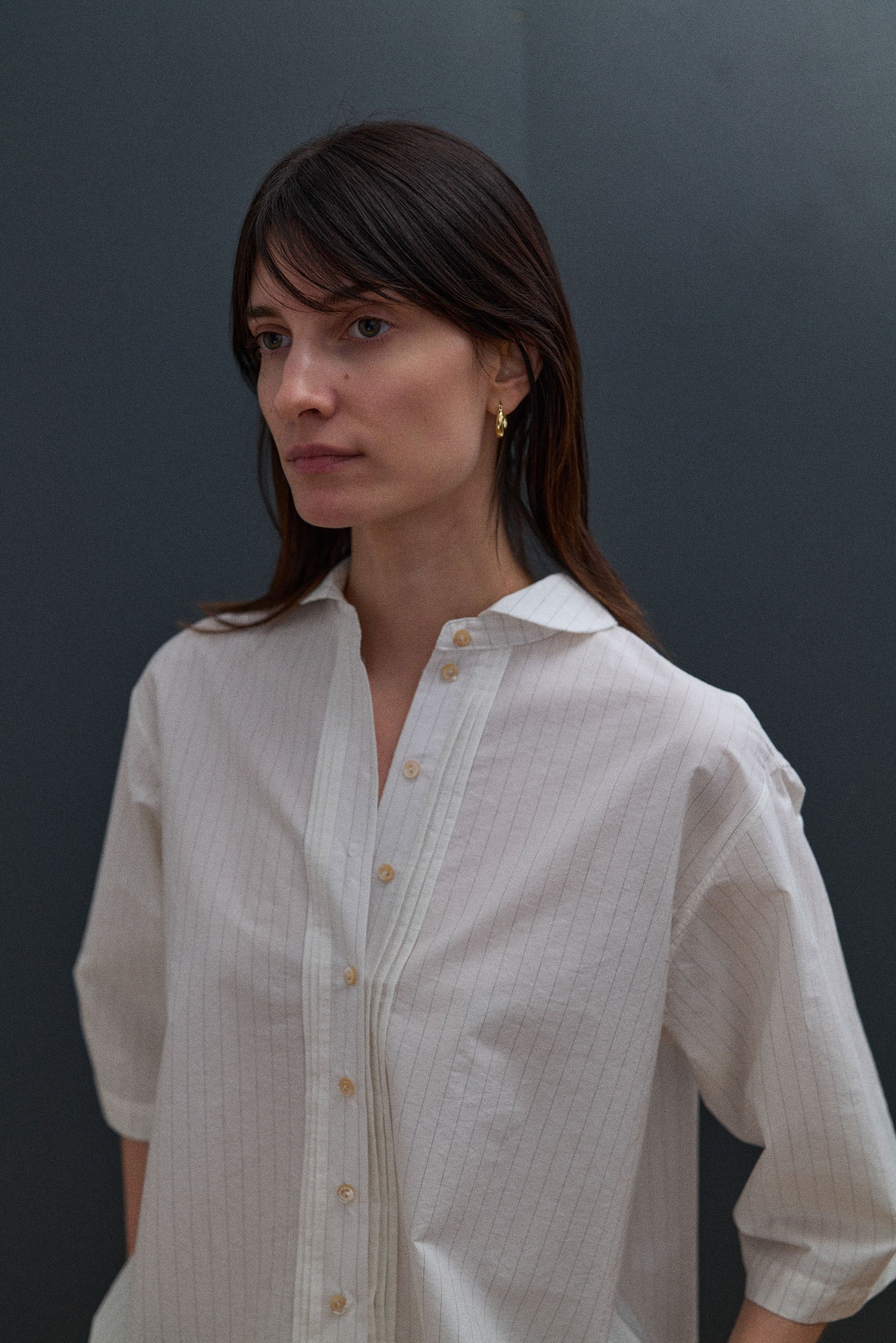 Woman wearing a light-colored shirt against a dark background