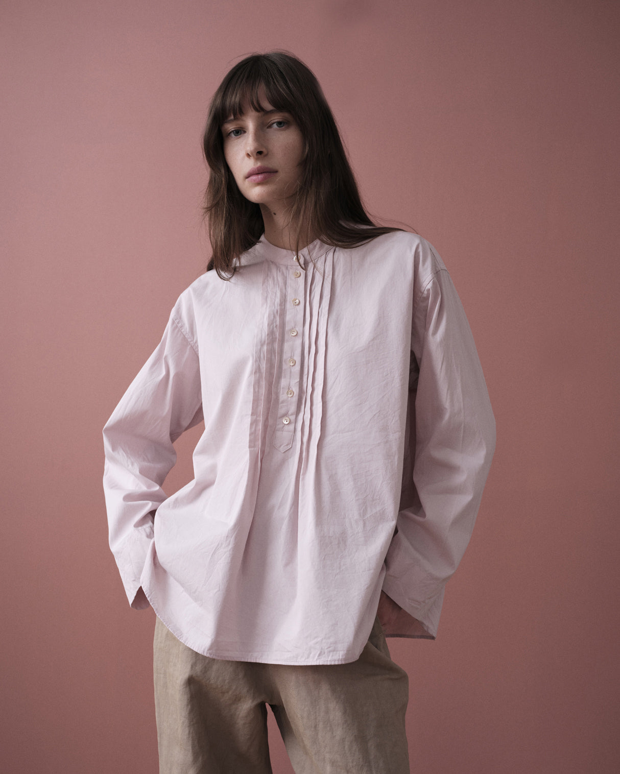 Woman wearing a light pink shirt against a pink background
